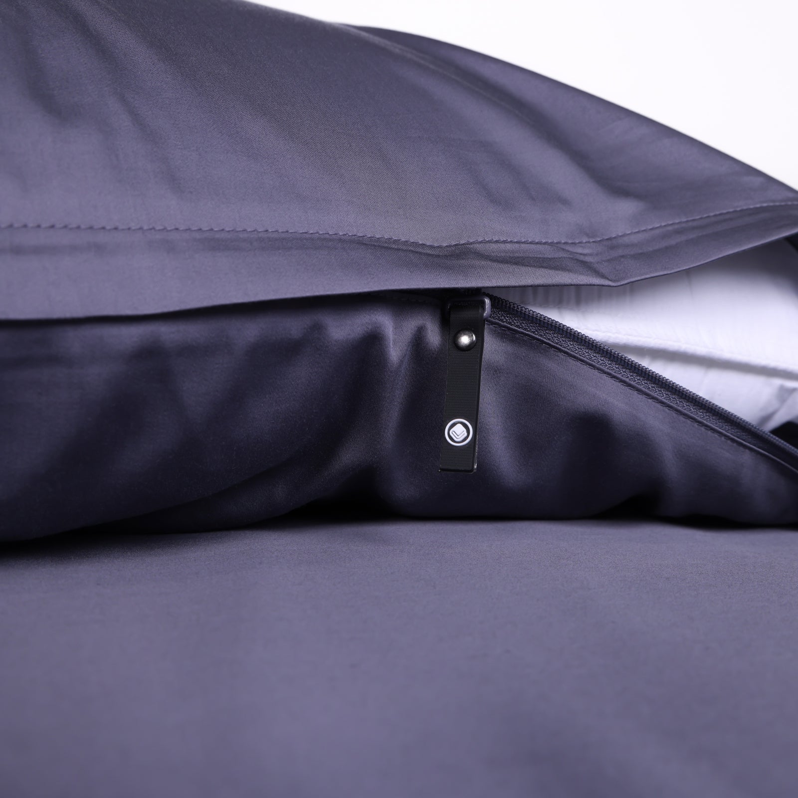 Close-up of a dark grey invisible zip pillowcase with discreet branded zipper pull, showcasing sleek, minimalist bedding design from The Lad Collective.