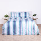 White, blue and teal striped duvet cover set with matching pillowcases, styled on bed with modern bedside tables.