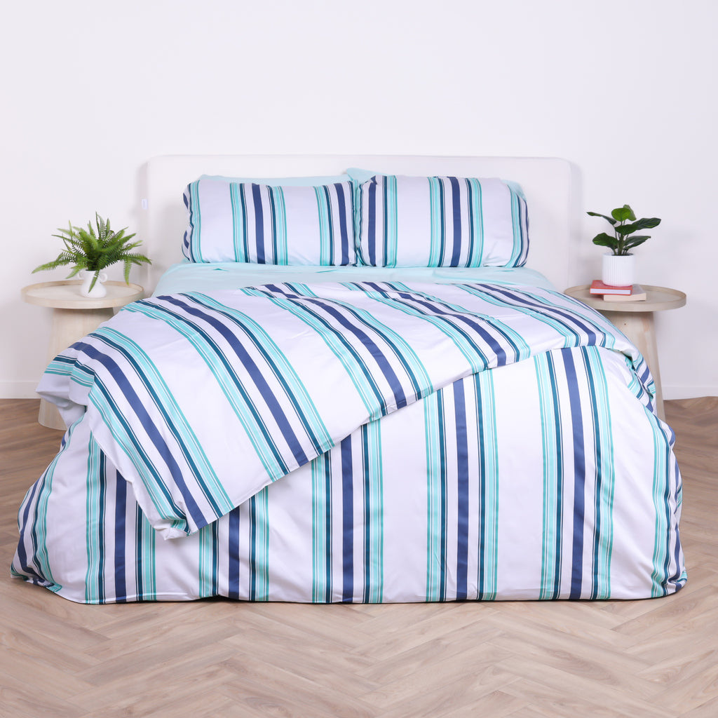 White, blue and teal striped duvet cover set with matching pillowcases, styled on bed with modern bedside tables.
