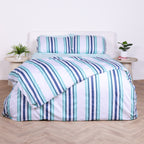 White, blue and teal striped duvet cover set with matching pillowcases, styled on bed with modern bedside tables.