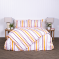 White, yellow and burnt orange striped duvet cover set with matching pillowcases, styled on modern bed with wooden bedside tables.