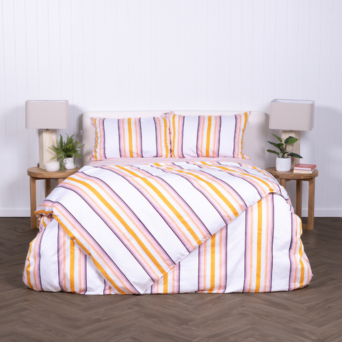 White, yellow and burnt orange striped duvet cover set with matching pillowcases, styled on modern bed with wooden bedside tables.