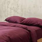 Burgundy colour Quilt Cover on bed with Stone Background 