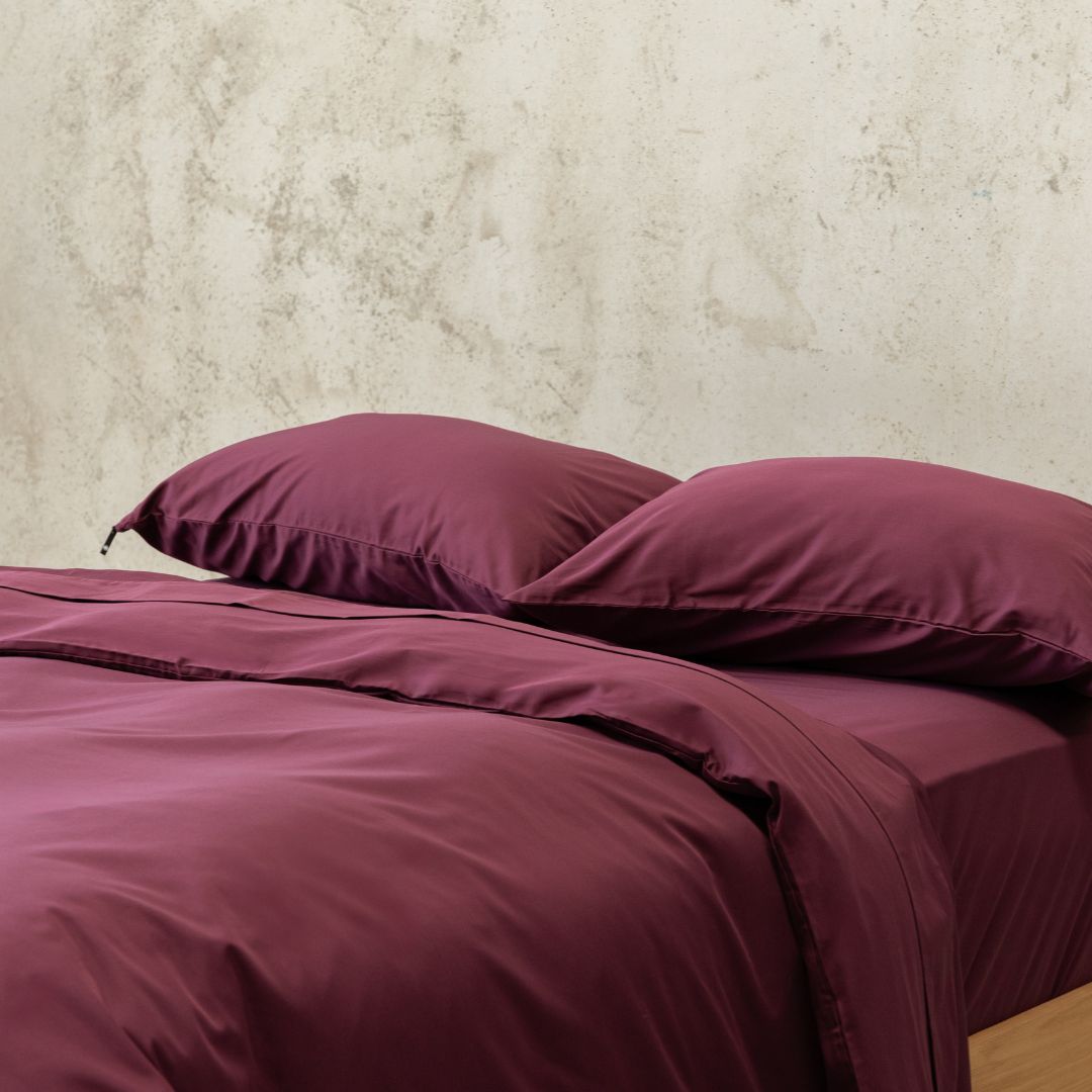 Burgundy colour Quilt Cover on bed with Stone Background 