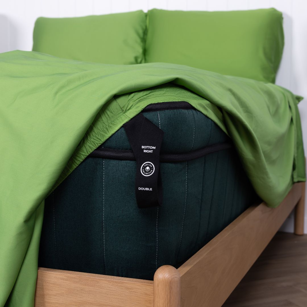 Black labeled corner loop hanging off bed with green fitted sheet.