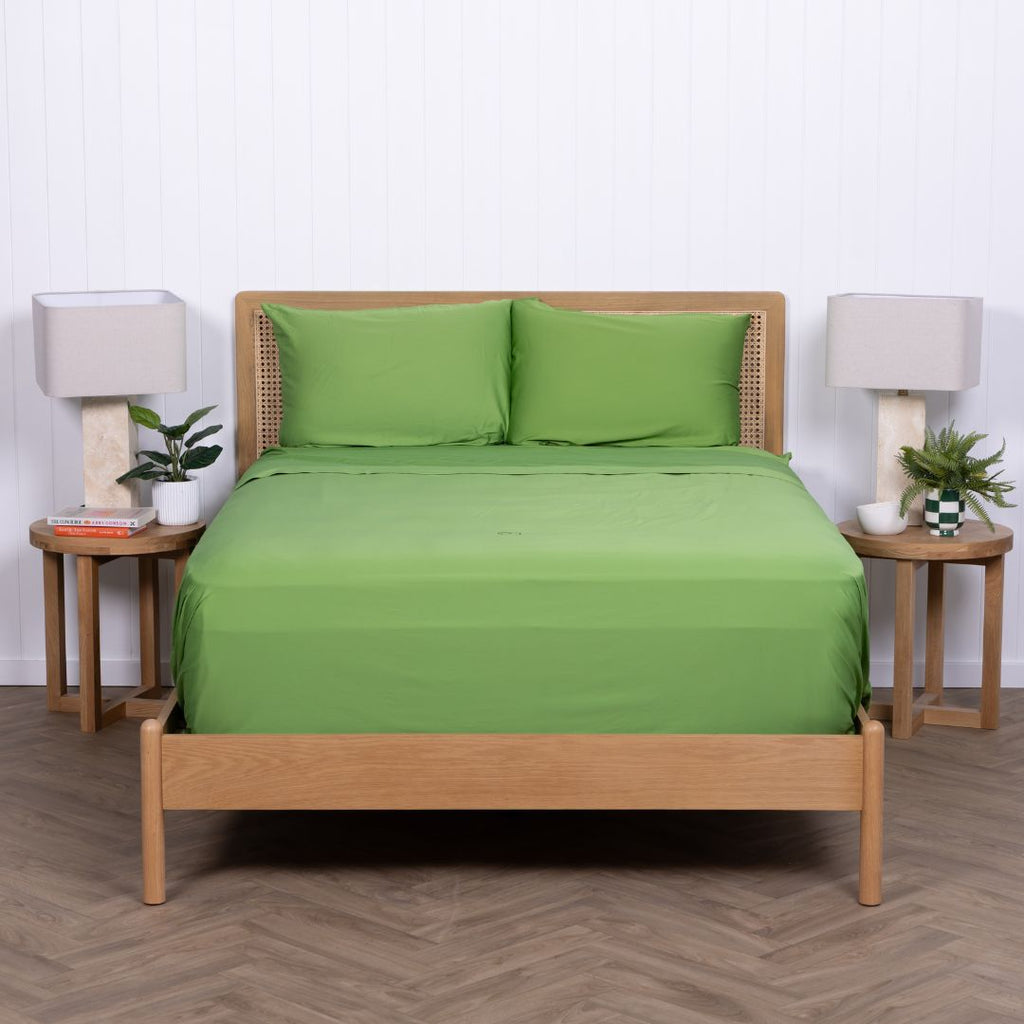 Minimalist shot of green TLC bedding neatly tucked into wooden bed frame.