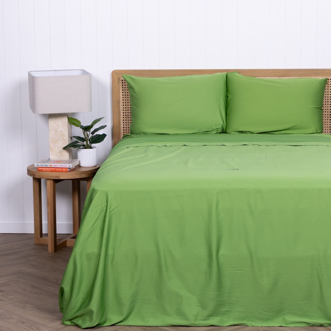 Green Colorado bedding set with two pillows and modern wooden side table.