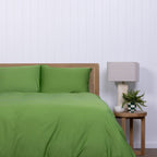 Colorado green duvet cover and pillow styled on bed with checkered vase on bedside table.