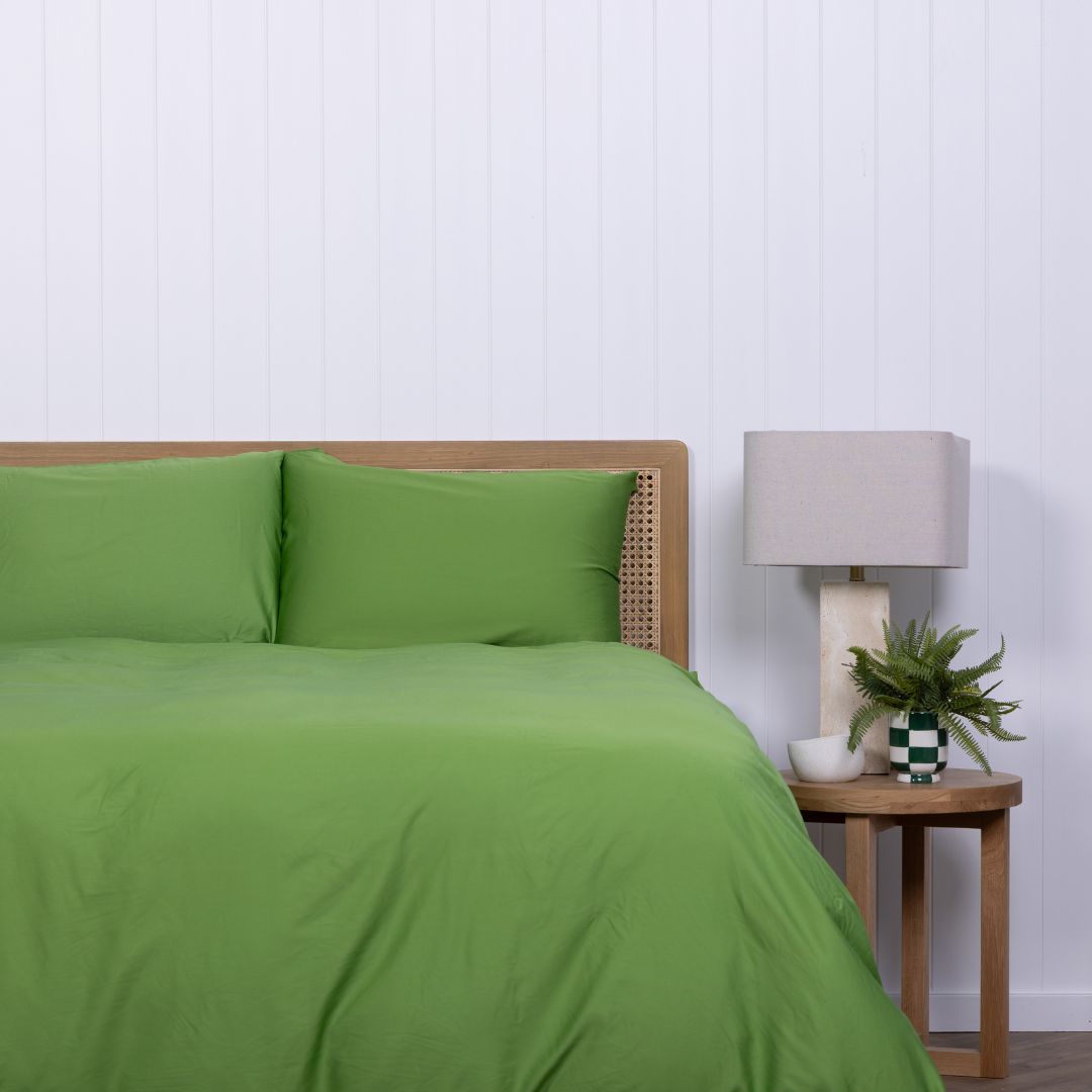 Colorado green duvet cover and pillow styled on bed with checkered vase on bedside table.