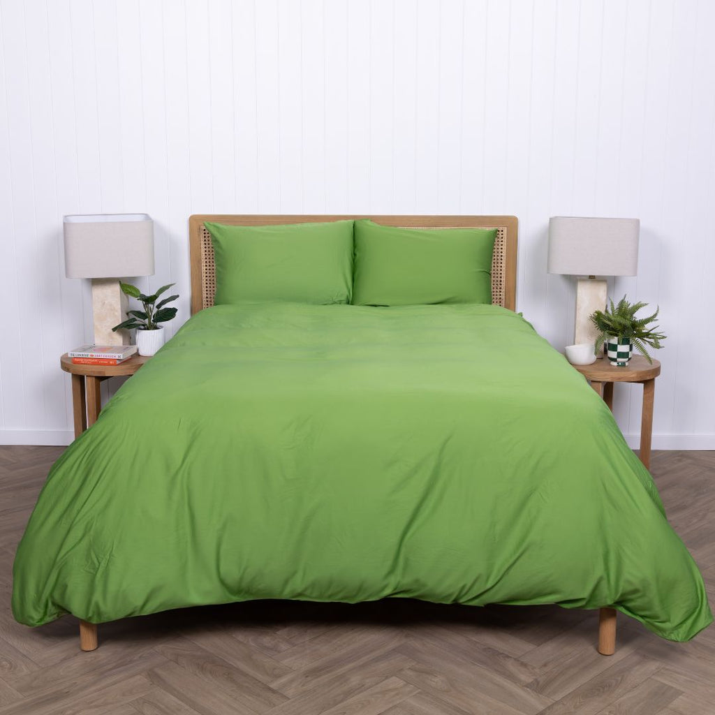 Full shot of bed dressed in Colorado green duvet cover with natural decor elements. 