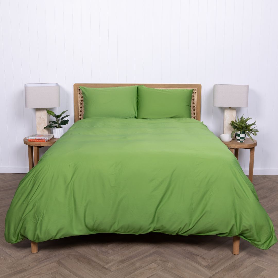 Full shot of bed dressed in Colorado green duvet cover with natural decor elements. 