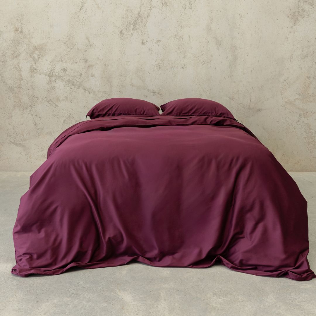 Burgundy colour Quilt Cover on bed with Stone Background 