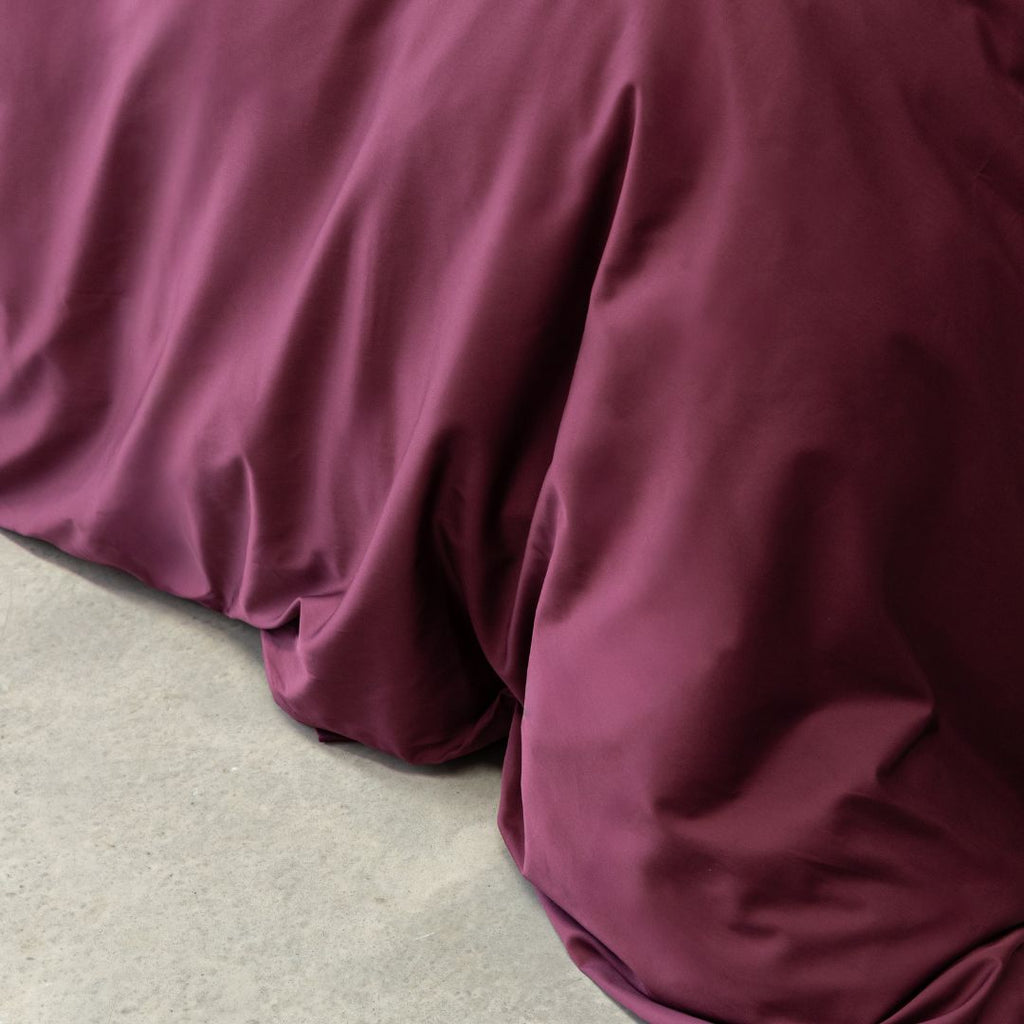Burgundy colour Quilt Cover on bed with Stone Background 