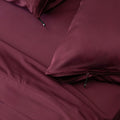 Burgundy colour Quilt Cover + pillowcases on bed with Stone Background 