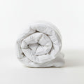 Rolled-up white comforter on a white background