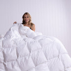Woman lying under a white comforter in a bedroom setting.