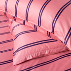 Pink bed sheets with purple stripes on a soft focus background.