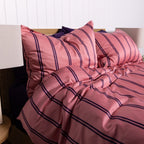 Pink striped bedding set on a bed with a white headboard.