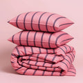 Pink striped bedding set with two pillows on a pink background.