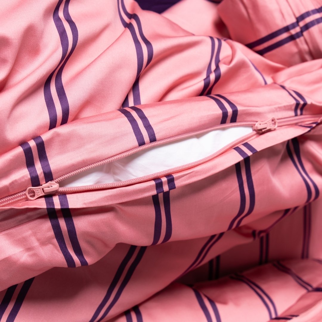 Close-up of a pink duvet cover with purple stripes and a zipper.