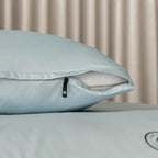 Light blue pillow with zipper on a neutral background.