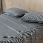 Navy and white pinstripe bedding set, close up of pillowcases on bed.