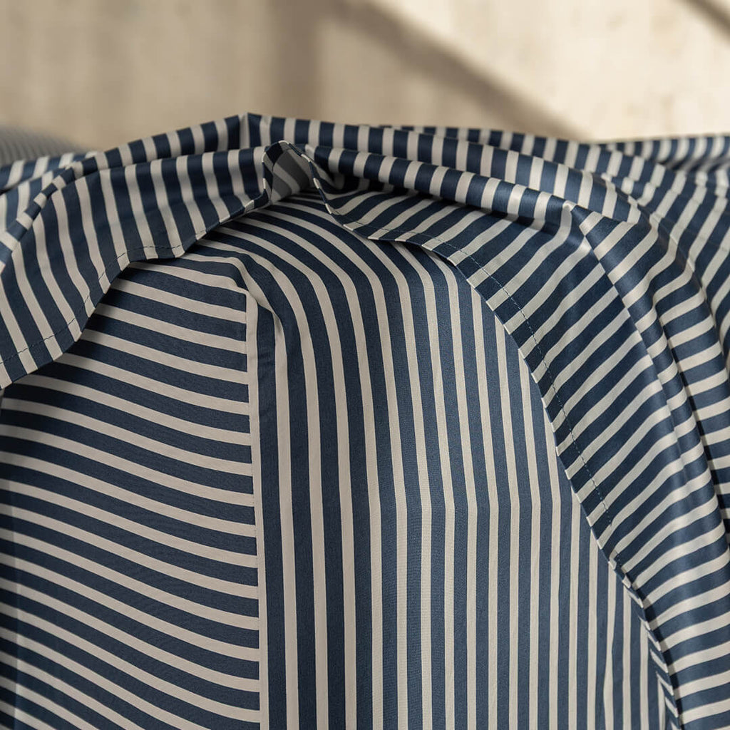 Navy and white pinstripe fitted sheet corner on mattress.