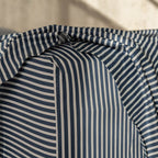 Navy and white pinstripe fitted sheet corner on mattress.