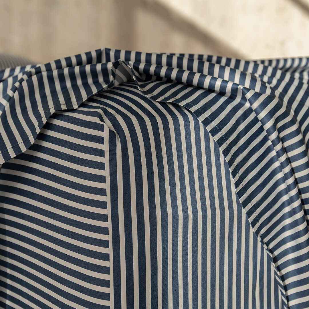 Navy and white pinstripe fitted sheet corner on mattress.