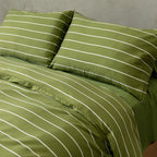 Green striped bedding set on a bed with a neutral background