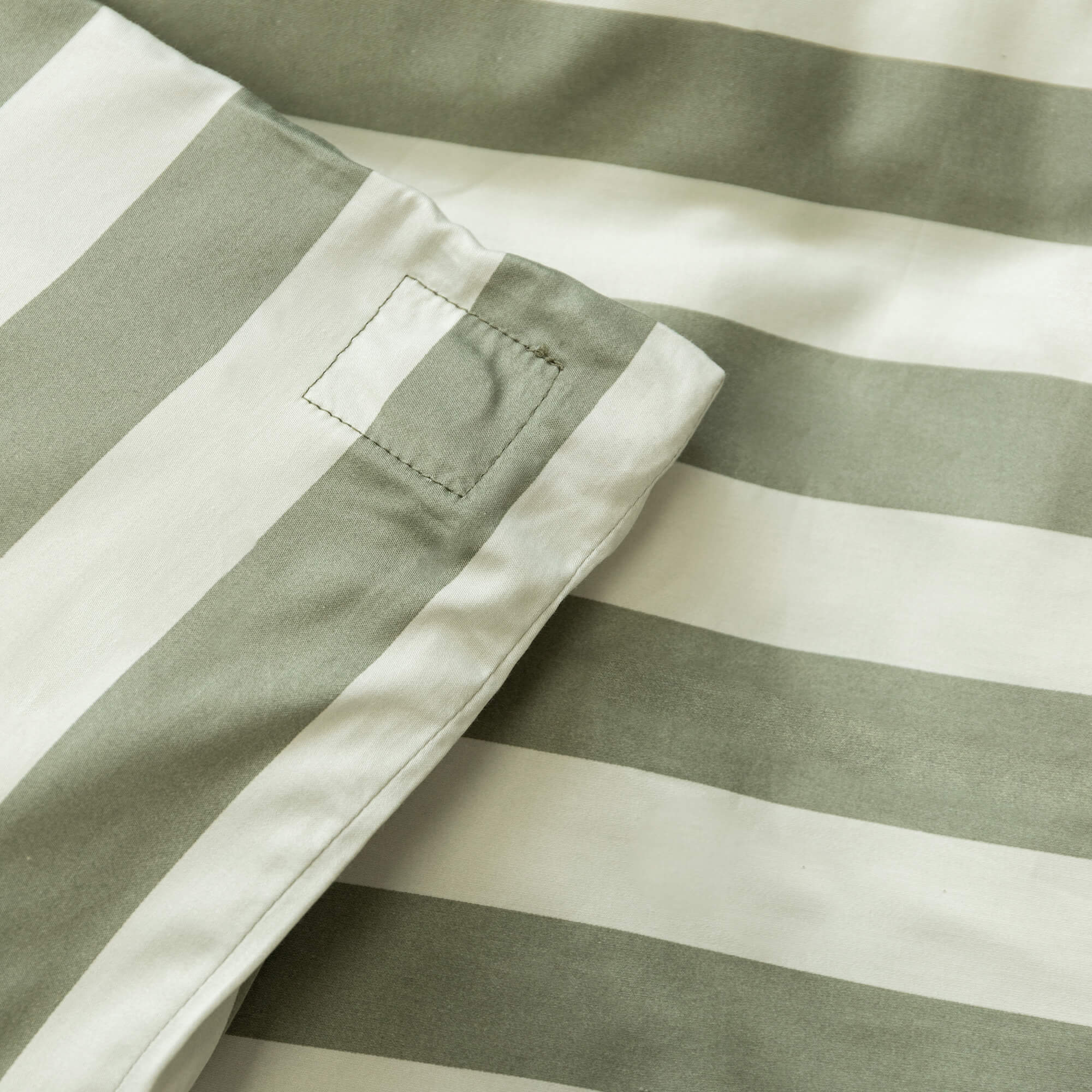 Close up of a sage green and light green stripe duvet cover magnetic corner. 