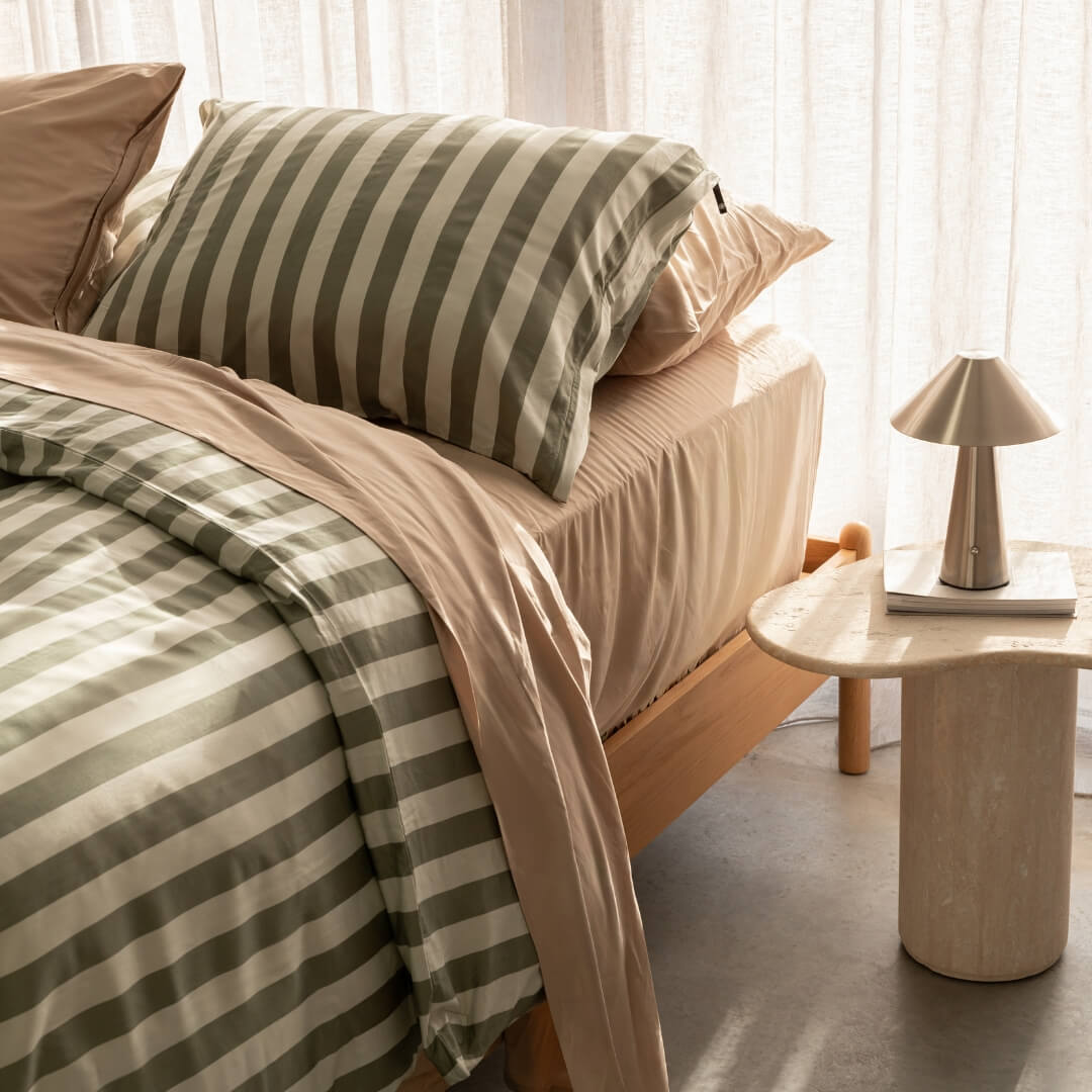 Montana stripe duvet cover paired with coral bed bedding set, against a beige curtain backdrop. A marble bed side table and lamp featured in the corner.