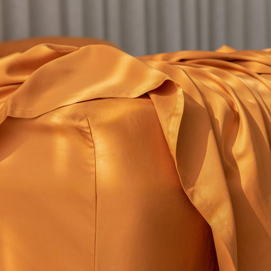 Close-up of a burnt orange fitted sheet corner on a bed.
