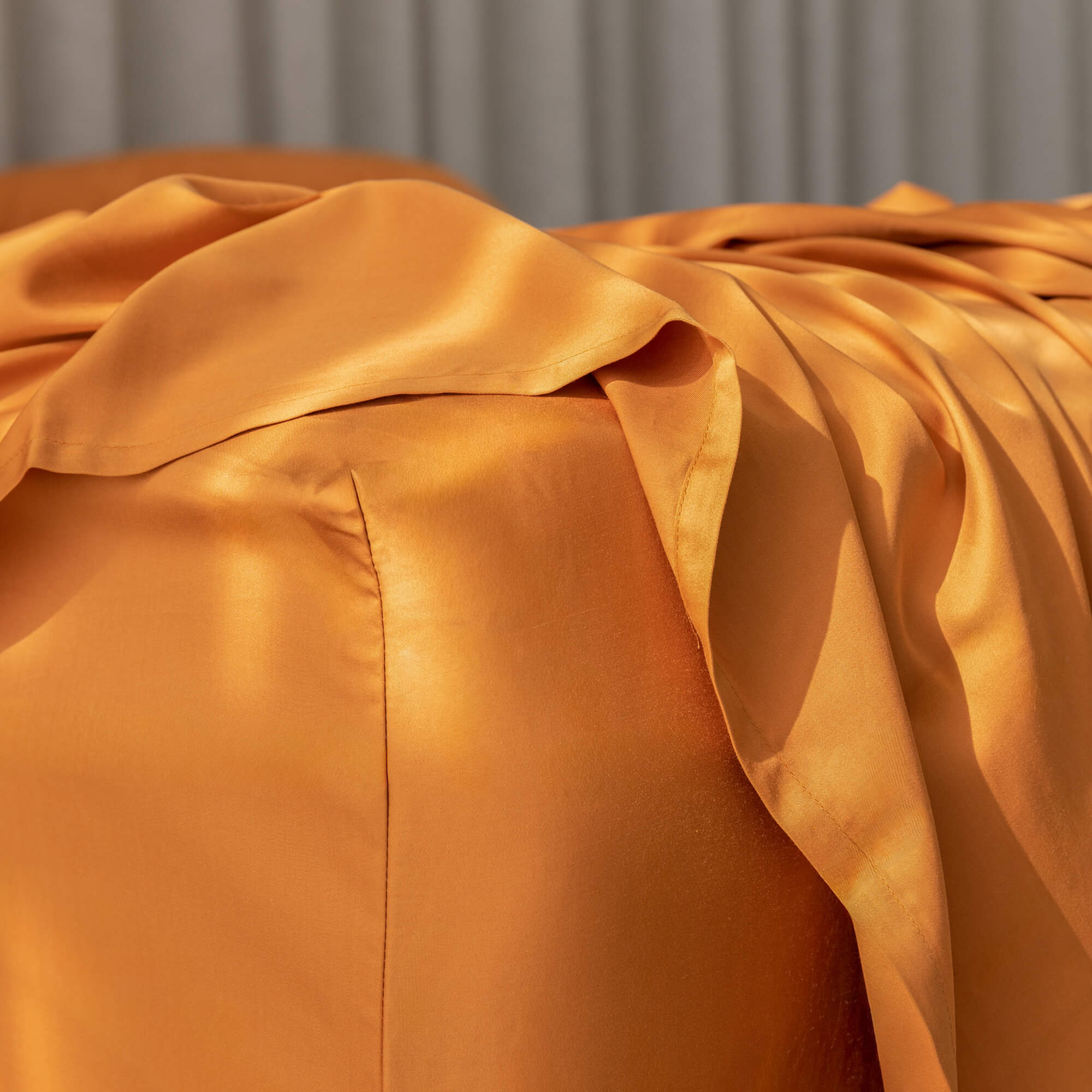 Close-up of a burnt orange fitted sheet corner on a bed.