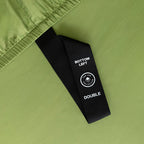 Close-up of a green fabric with a black label on a matching green background