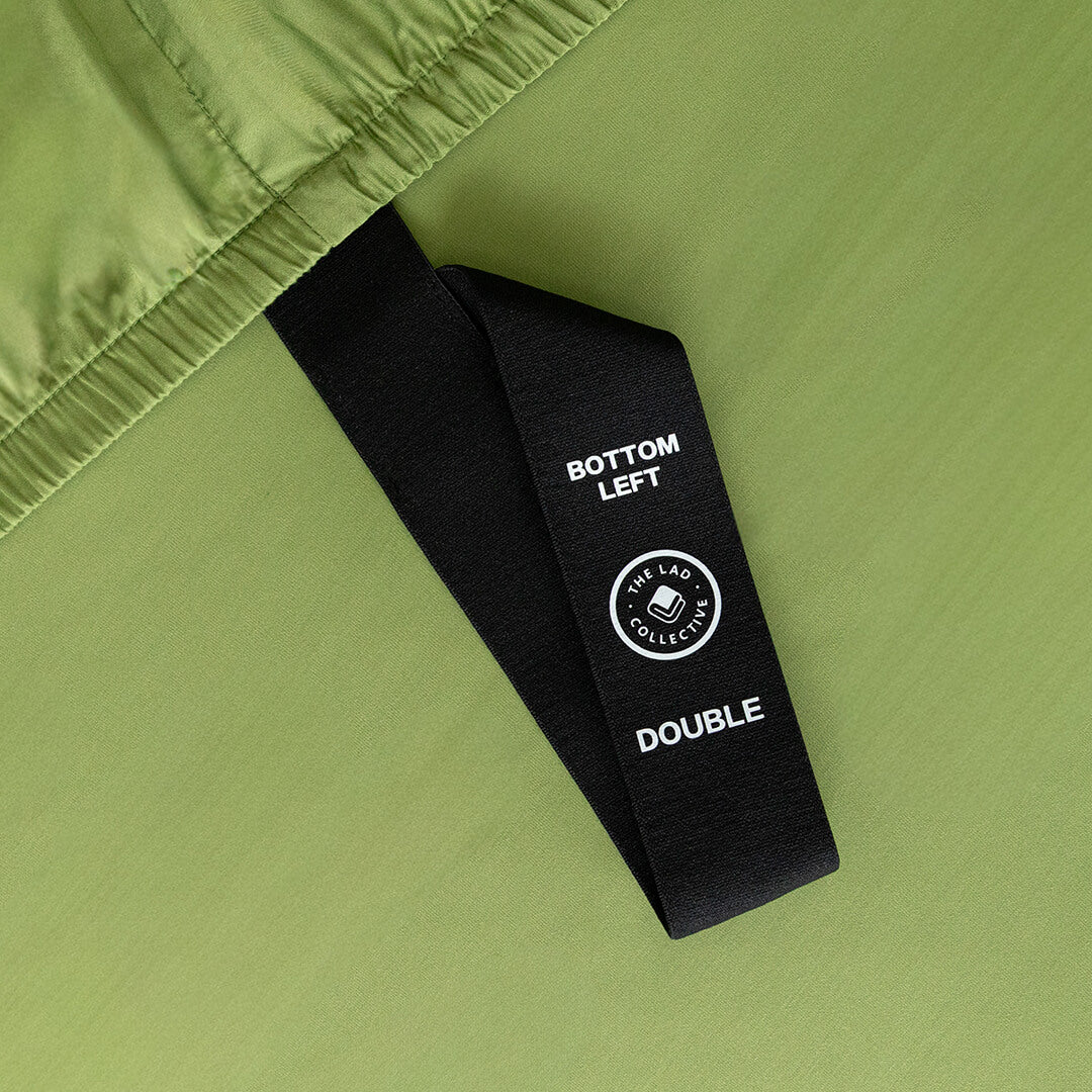 Close-up of a green fabric with a black label on a matching green background