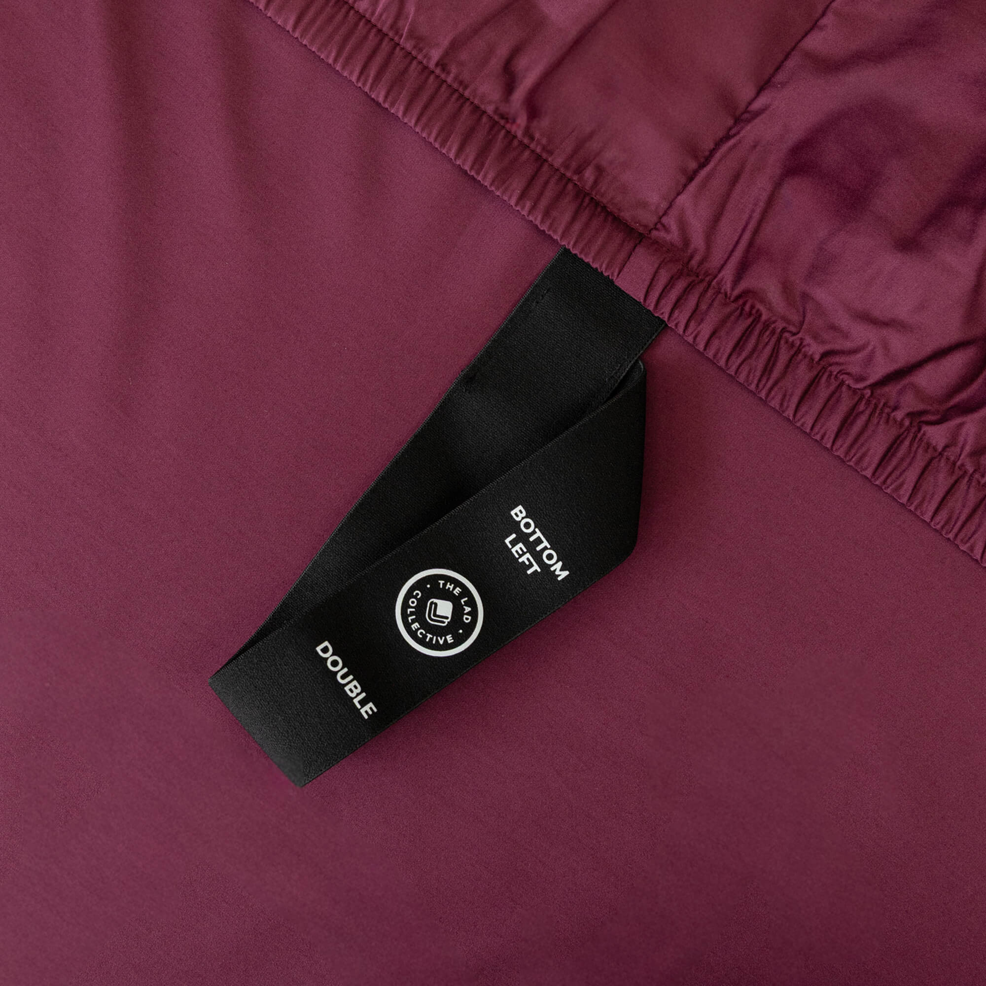Close-up of a maroon fabric with a black label featuring text and a logo.