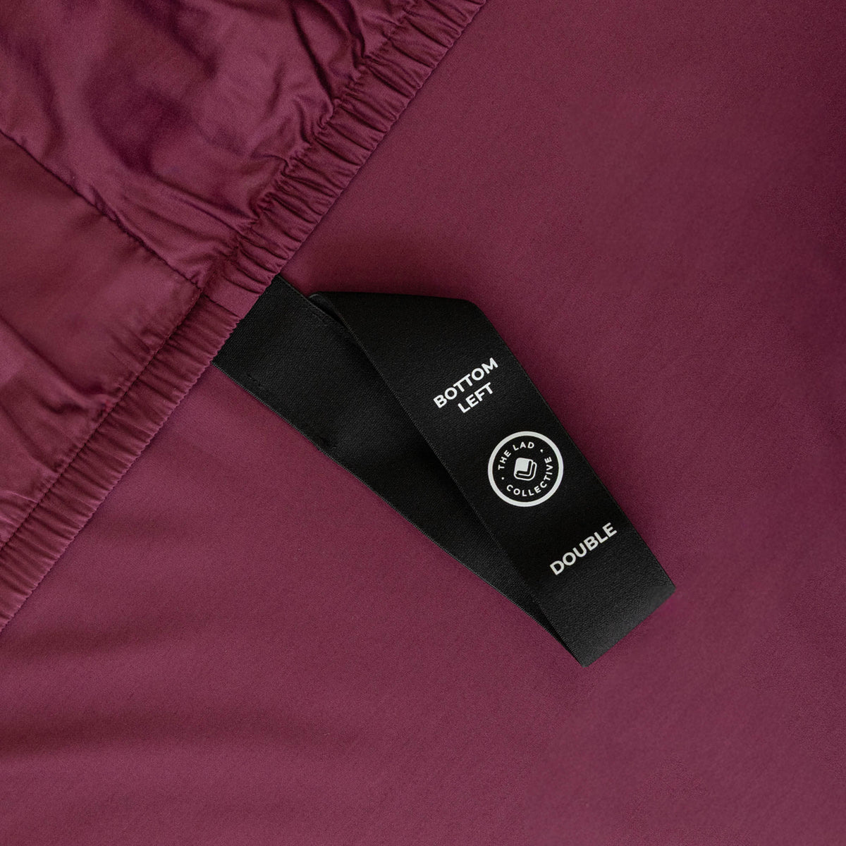 Close-up of a maroon fabric with a black label featuring text and a logo.