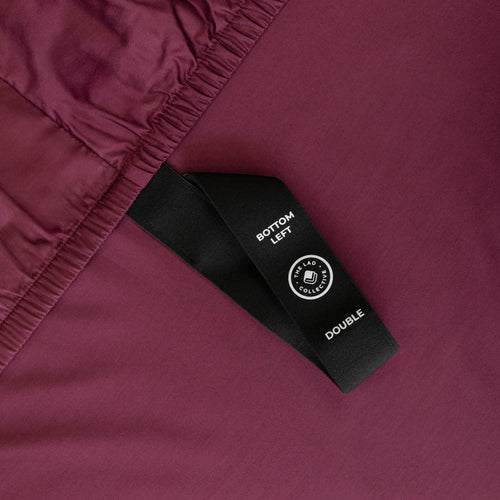 Close-up of a maroon fabric with a black label featuring text and a logo.