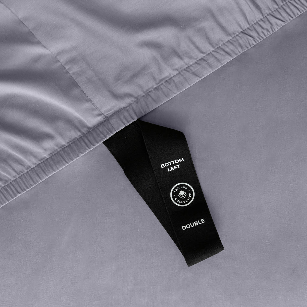 Close up of corner strap of fitted sheet in grey coloured bedding