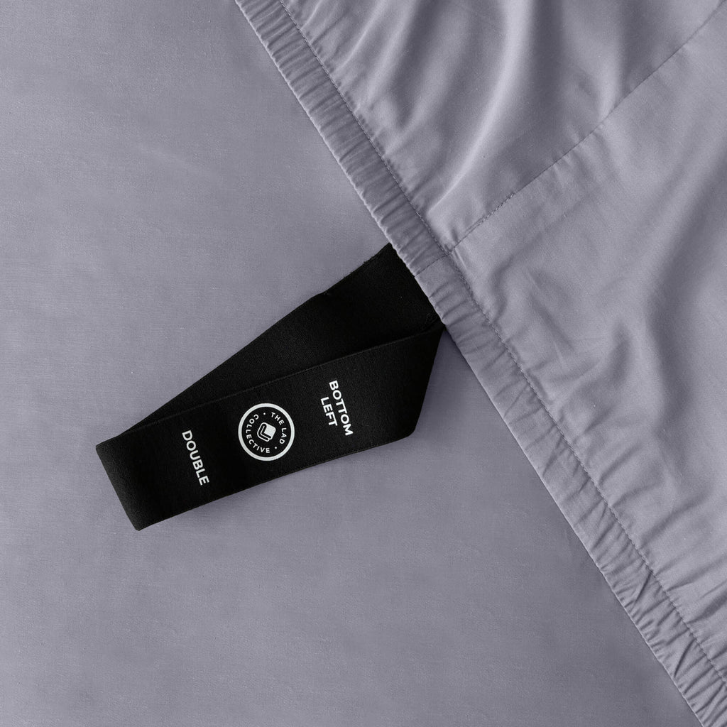 Close up of corner strap of fitted sheet in gray coloured bedding