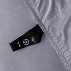 Close up of corner strap of fitted sheet in gray coloured bedding