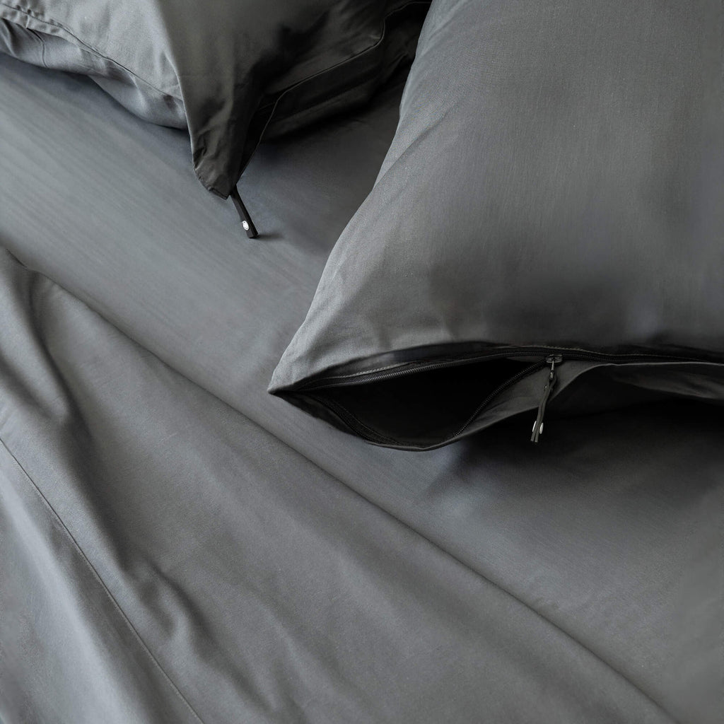 Gray bedding set with pillows on a bed.
