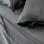 Gray bedding set with pillows on a bed.