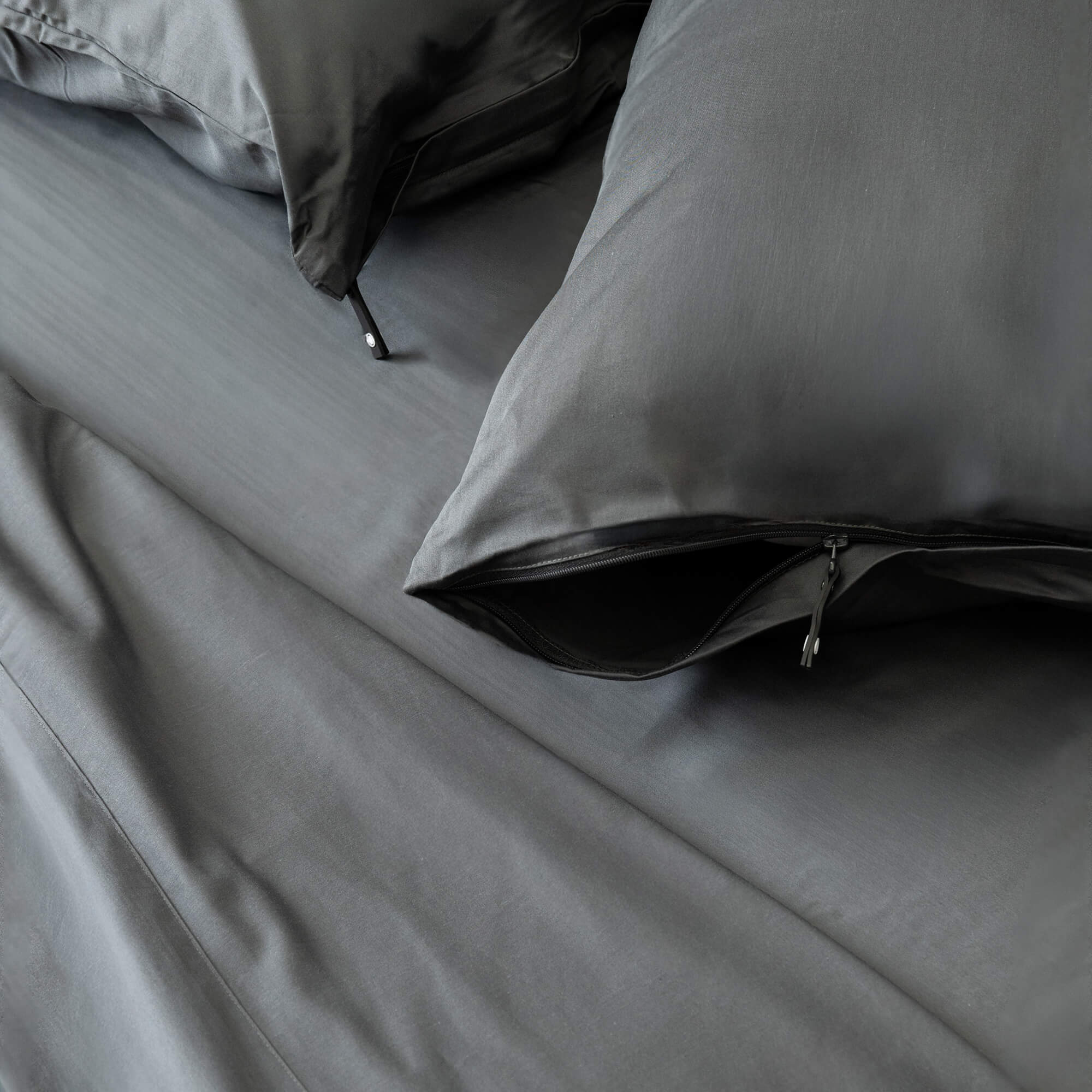 Gray bedding set with pillows on a bed.