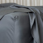 Charcoal gray fitted sheet on a bed, zoomed in on the corner. 