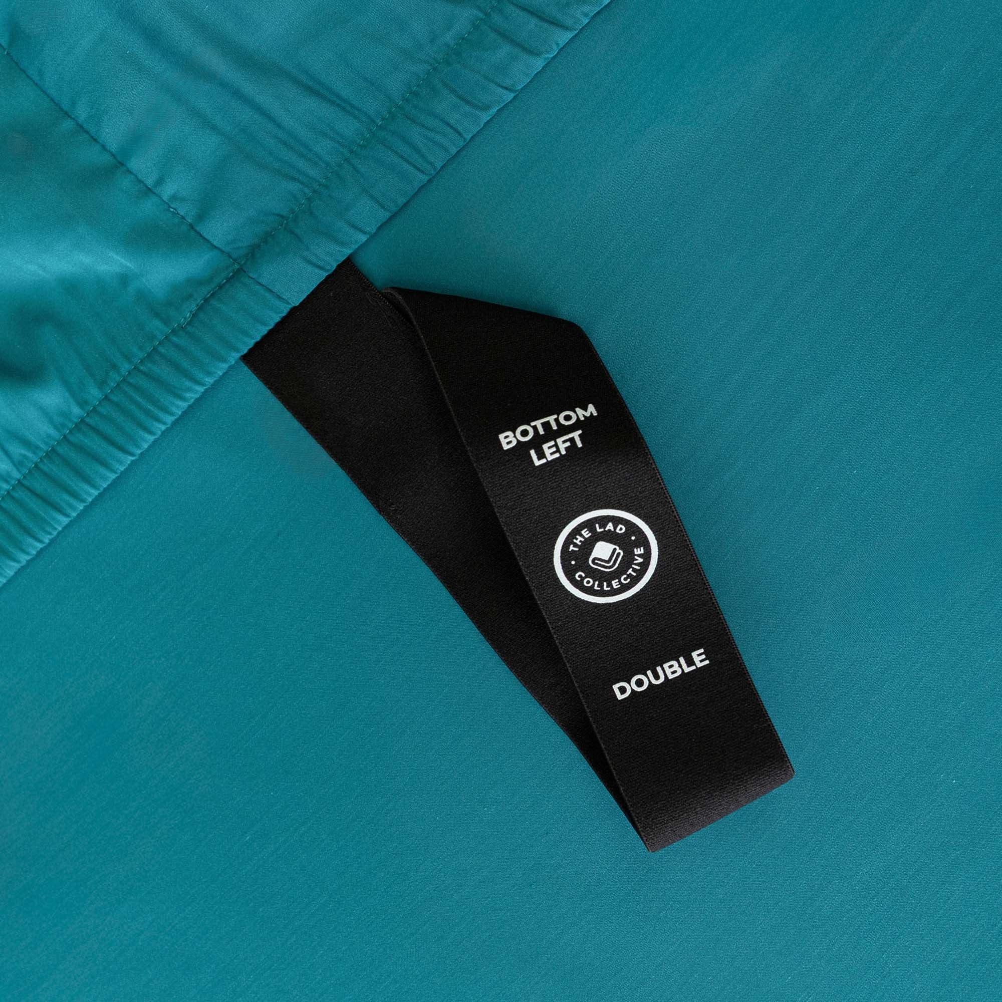 Close-up of a teal fabric with a black label on a matching teal background