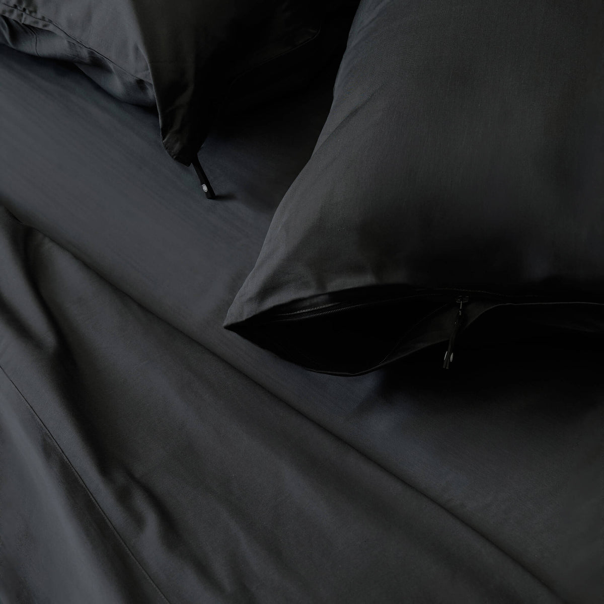 Black bedspread on a bed with a neutral background