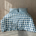 Blue and white checkered duvet set on a bed against a neutral wall.