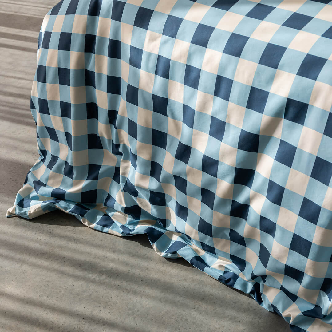 Blue and beige checkered bedspread on a bed with a wooden headboard.